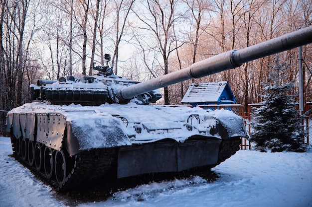 Tank under the snow in the forest Winter tank camouflage Battle tank in the snow on the roadside of highway War in Ukraine in winter