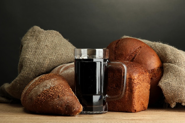 Tankard of kvass and rye breads on wooden table on grey background