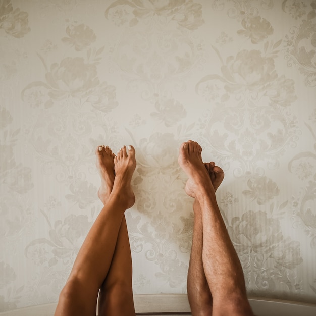 Photo tanned male nude and female legs crossed raised up against wall