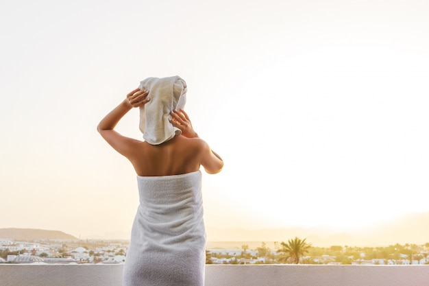 Tanned tender girl stands on the terrace with a beautiful view of the mountains