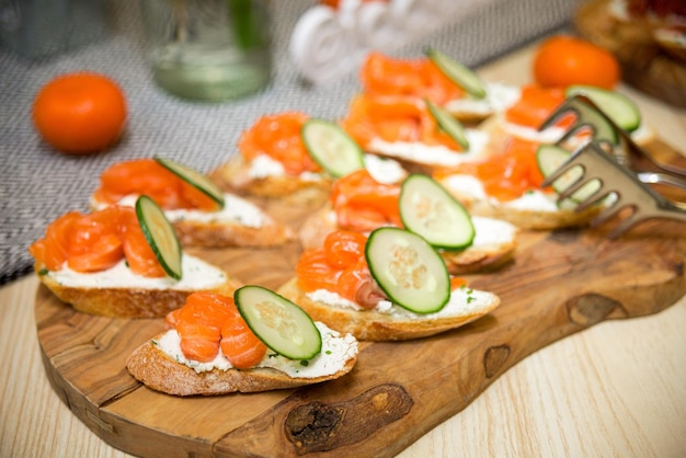 Tapas with salted salmon and cucumber on a wooden board