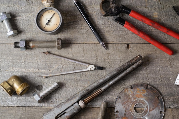 Tapemeasure internal screws bolts manometer diamond wheel pliers pipe wrench on old wooden table Top view Copy space