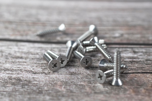 Photo tapping screws made of steel on wood background metal screw iron screw chrome screw screws as a background wood screw concept industry copy space for text