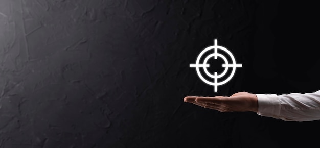 Targeting concept with businessman hand holding target icon dartboard sketch on chalkboard. Objective target and investment goal concept.