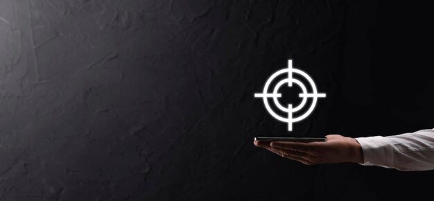 Targeting concept with businessman hand holding target icon dartboard sketch on chalkboard. Objective target and investment goal concept.