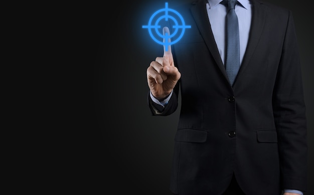 Targeting concept with businessman hand holding target icon dartboard sketch on chalkboard. Objective target and investment goal concept.