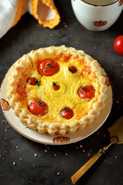 Photo tart pie with cheese, eggs, cream and cherry tomatoes on puff pastry