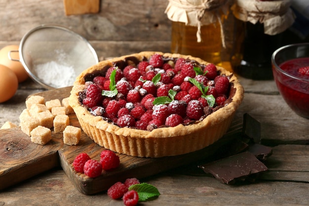 Tart with fresh raspberries on wooden background