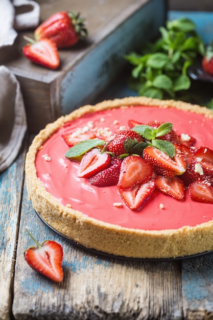 Tart with strawberries and whipped mascarpone cream decorated with fresh strawberry over wooden rustic