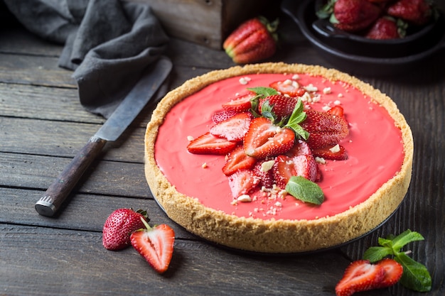 Tart with strawberries and whipped mascarpone cream decorated with fresh strawberry over wooden rustic