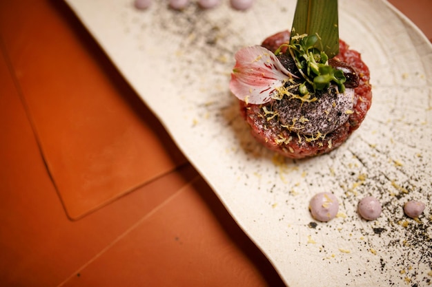 tartar on a green sheet on a white plate. juicy tasty tartare with sauce.