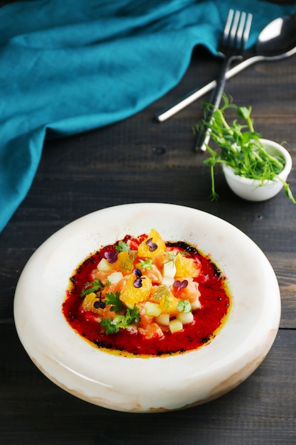 Tartar salmon in white ceramic plate on wooden background