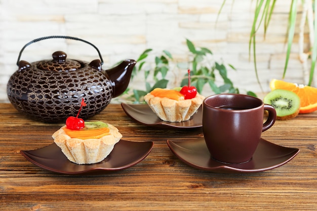 Tartlets with fruits and tea on a  wooden table