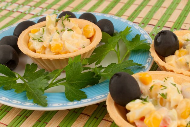 Tartlets with salad and olives on a blue plate