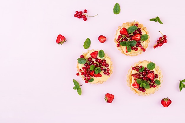 Tarts with strawberries, currant and whipped cream decorated with mint leaves, Top view