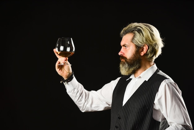 Tasting sediments Wine tasting Male skilled sommelier estimates alcoholic drink red wine in longstemmed wineglasses bearded man taste wine in restaurant Checking color and sediments of wine