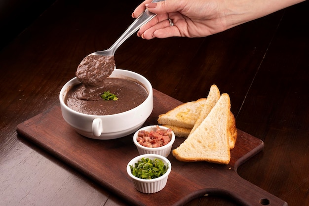 Tasting a spoon of bean broth with closeup and seasonings on cattail bacon chives wood closeup