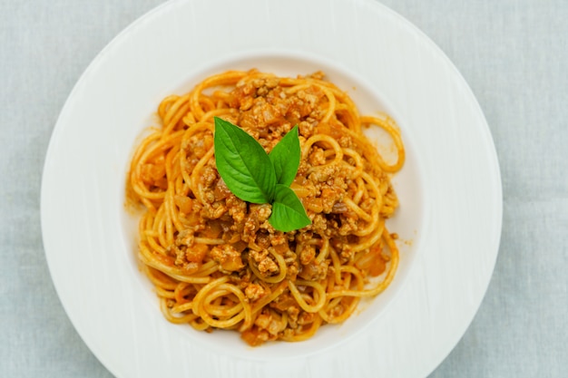 Tasty appetizing classic Italian spaghetti pasta with tomato sauce and basil on plate 