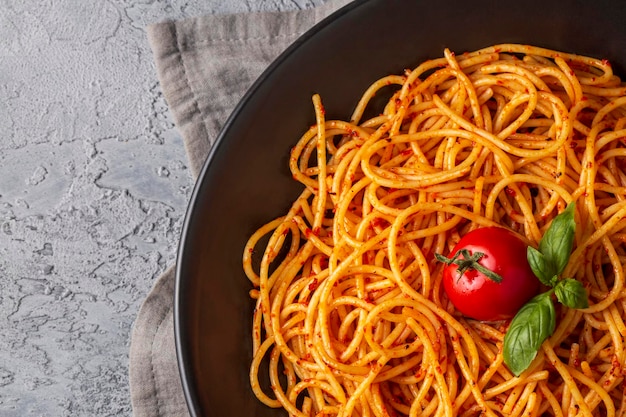 Tasty appetizing classic italian spaghetti pasta with tomato sauce, cheese parmesan and basil on plate and ingredients for cooking pasta on white marble table.