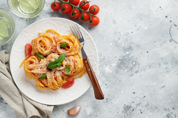 Tasty appetizing classic italian tagliatelle pasta with tomato sauce cheese parmesan and basil on pl...