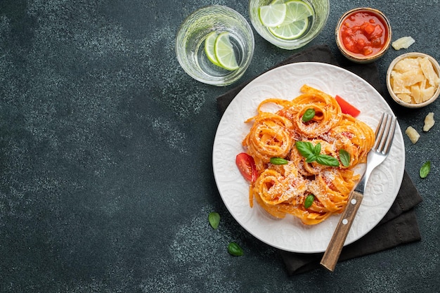 Tasty appetizing classic italian tagliatelle pasta with tomato sauce cheese parmesan and basil on pl...