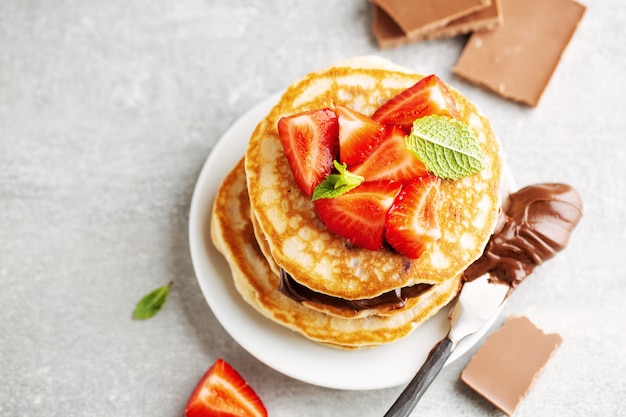 Tasty appetizing freshmade pancakes decorated with strawberry and chocolate paste served for breakfast. Closeup