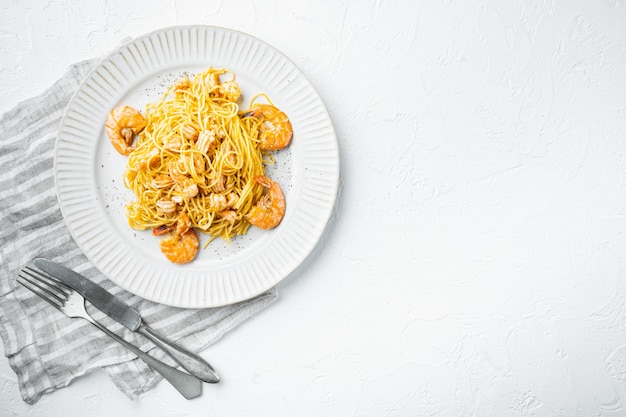 Photo tasty appetizing pasta spaghetti with pesto sauce and shrimps set, on plate, on white stone surface, top view flat lay, with copy space