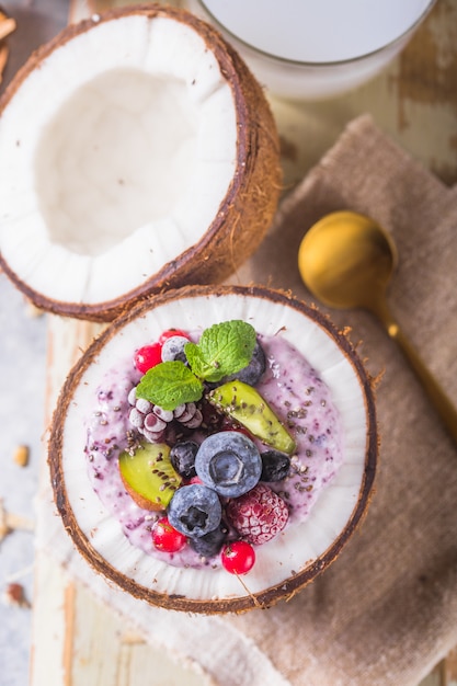 Tasty appetizing smoothie acai bowl made from blackberries and wild berries. Served in coconut bowl. Healthy life clean eating concept. Frozen dessert nice cream.