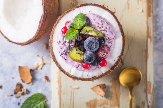 Tasty appetizing smoothie acai bowl made from blackberries and wild berries. Served in coconut bowl. Healthy life clean eating concept. Frozen dessert nice cream.