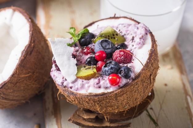 Tasty appetizing smoothie acai bowl made from blackberries and wild berries. Served in coconut bowl. Healthy life clean eating concept. Frozen dessert nice cream.