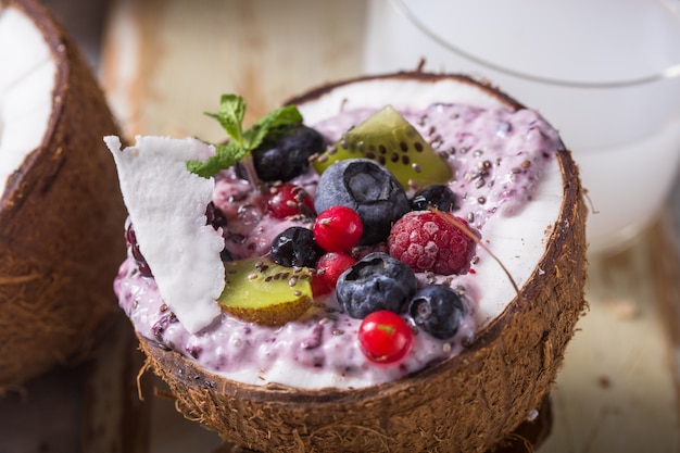 Tasty appetizing smoothie acai bowl made from blackberries and wild berries. Served in coconut bowl. Healthy life clean eating concept. Frozen dessert nice cream.