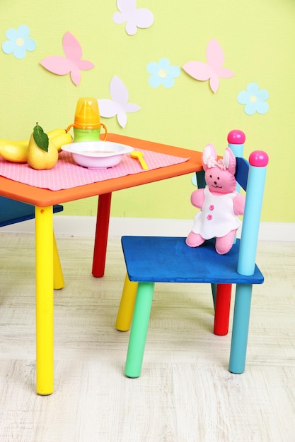 Tasty baby fruit puree and baby bottle on table in room