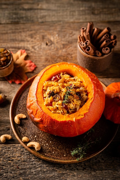 Tasty baked pumpkin stuffed with rice vegetables cashews and dried fruits on wooden table with dark