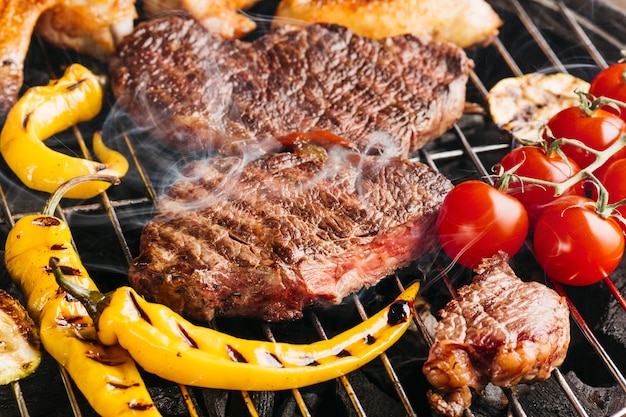 Tasty beef steaks on the grill with yellow chili and cherry tomato