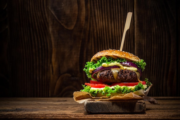 Tasty Big Burger in Bun on Wooden Background with Copy Space