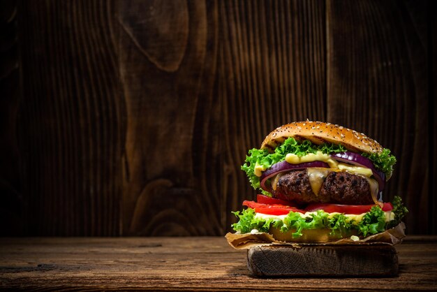 Tasty Big Burger in Bun on Wooden Background with Copy Space