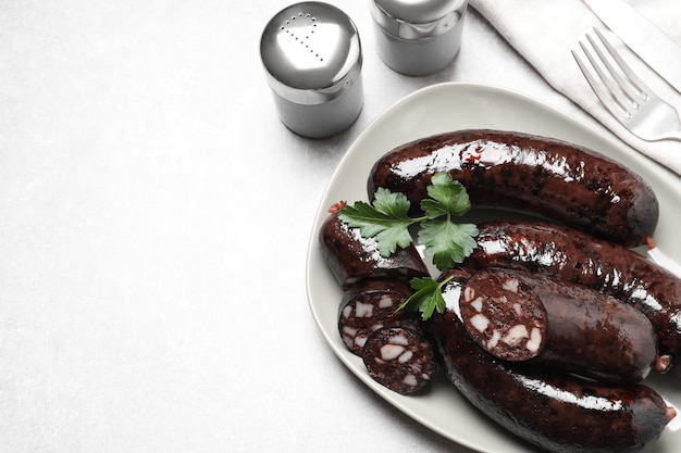 Tasty blood sausages with parsley served on light grey table flat lay Space for text