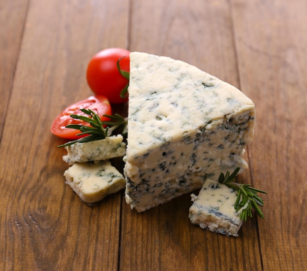 Tasty blue cheese with thyme and tomato on wooden table