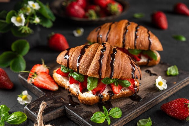 Photo tasty breakfast croissants with strawberries cream cheese basil and chocolate sauce with flowers on