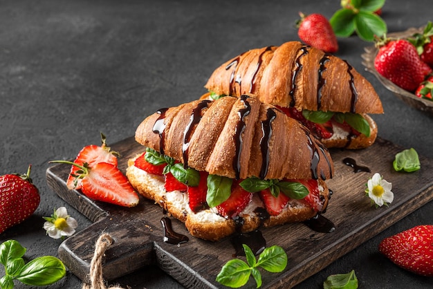 Photo tasty breakfast croissants with strawberries cream cheese basil and chocolate sauce with flowers on