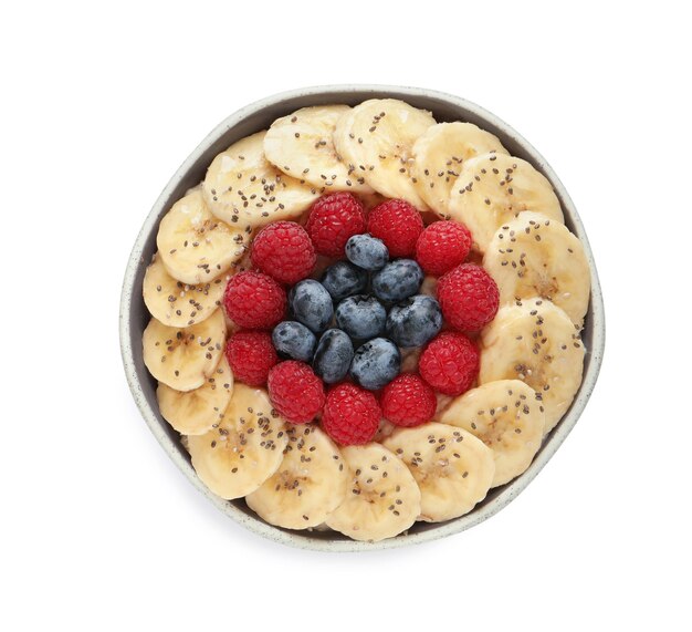 Tasty breakfast with berries banana and chia seeds in bowl on white background top view