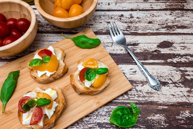 Tasty bruschetta with mozzarella tomato basil and oil Bread on a wooden cutting board