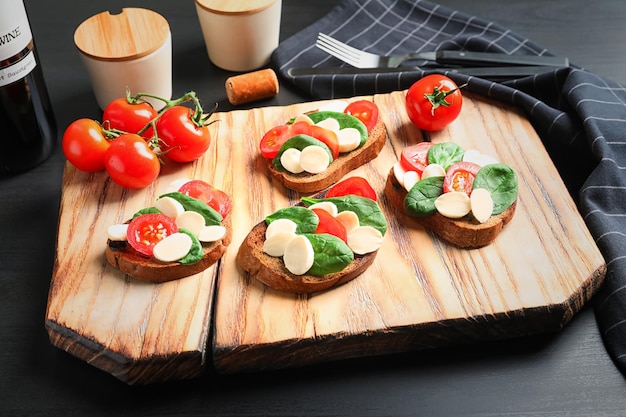 Tasty bruschettas with cherry tomatoes and mozzarella on wooden board