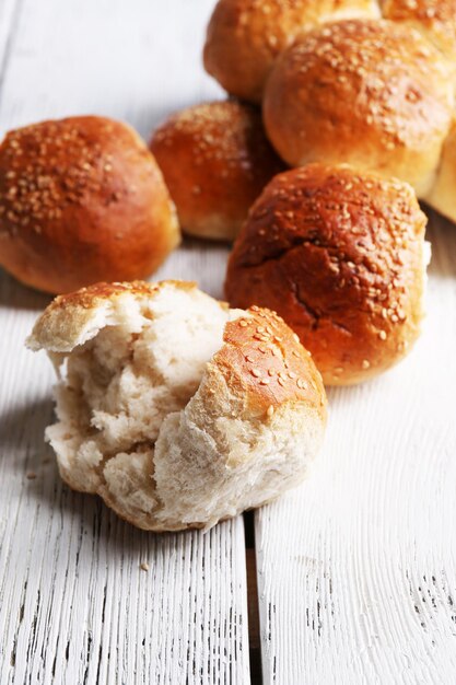 Tasty buns with sesame on color wooden background