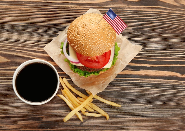 Tasty burger with coke fries and American flag on table