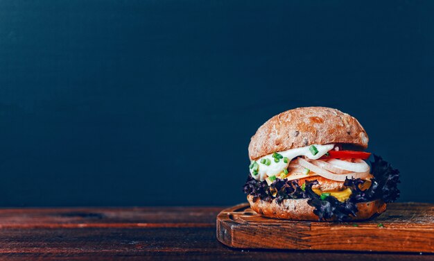 Tasty burger on wooden cutting board