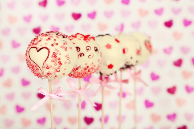 Photo tasty cake pops on color background