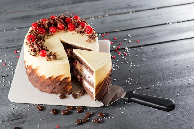 Tasty cake with chocolate and cherries in wooden background