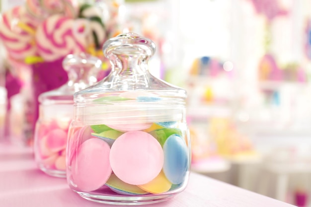 Tasty candies in jar on table