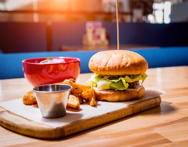 Tasty cheeseburger and chips on the wooden table. Restaurant.